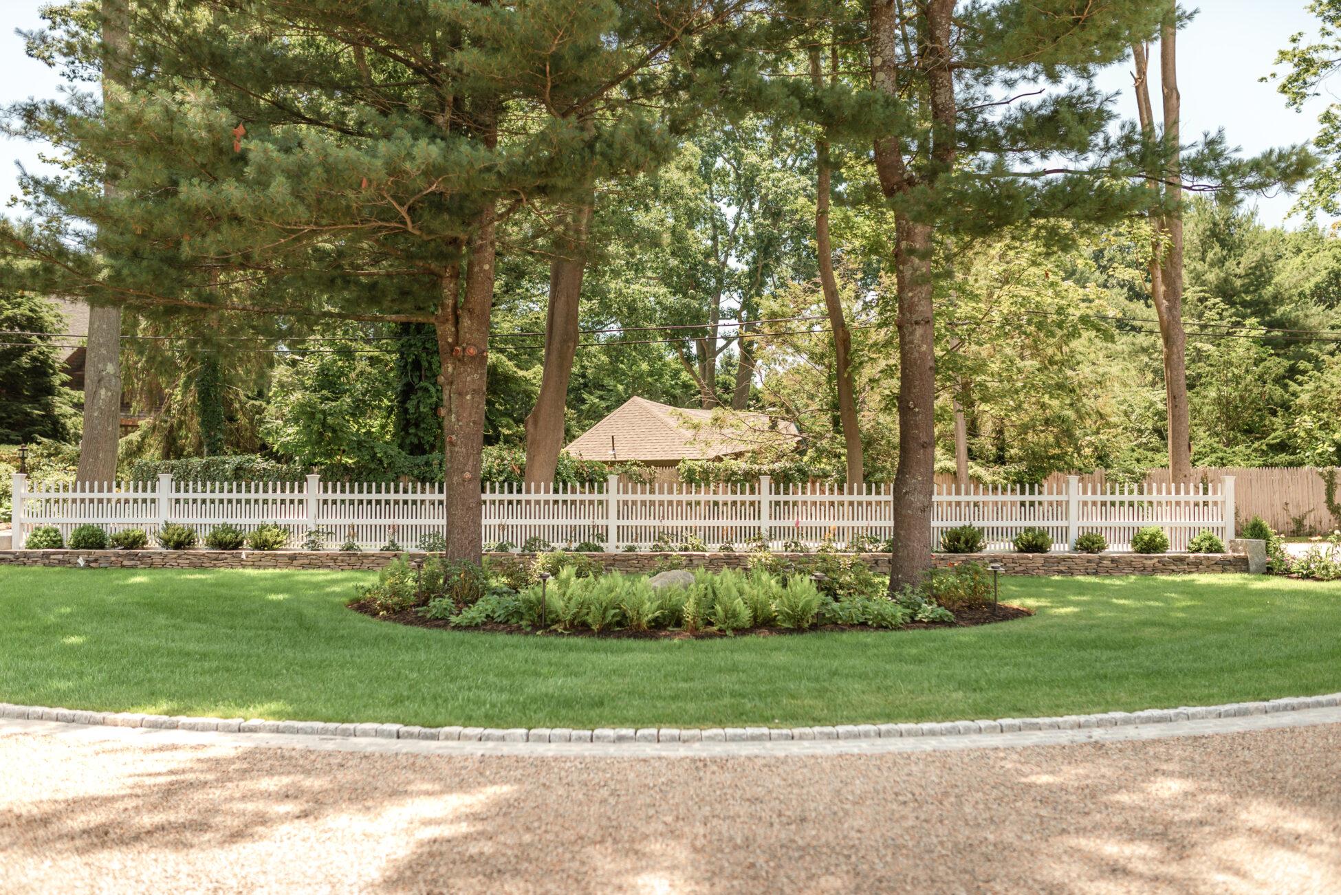 landscape garden in front of white picket fence
